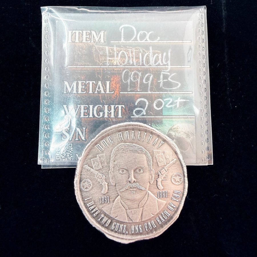 A two-ounce Doc Holliday silver round showing his portrait, two revolvers and playing cards, beside its labeled sleeve